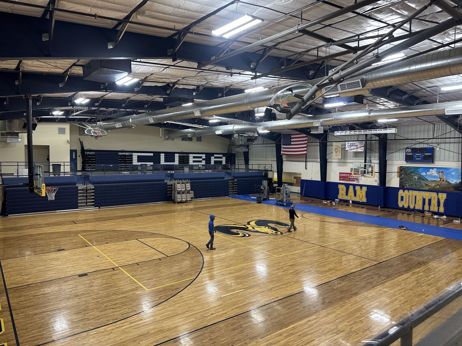 School gymnasium with wall-mounted scoreboard and newly installed lighting